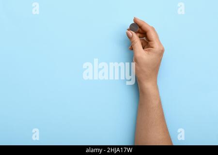 Frau mit Lithium-Knopfzellenbatterie auf blauem Hintergrund Stockfoto