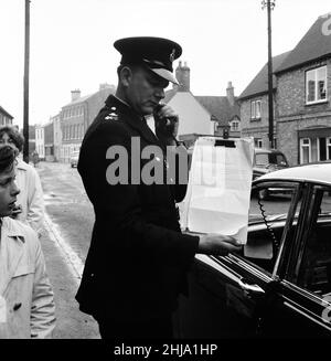 Polizeiwagen, ausgestattet mit einer Lautsprechereinheit, ruft am Mittwoch, den 14th. August 1963, im Dorf Brill zur Information auf. Unser Bild Zeigt ... Polizist hält die Zwischenablage mit dem Drehbuch, das er benutzt, um für Informationen zu appellieren. Der große Eisenbahnraub von 1963 war der Raub von 2,6 Millionen Pfund von einem Royal Mail-Zug, der von Glasgow nach London auf der West Coast Main Line in den frühen Morgenstunden des 8th. August 1963 an der Bridego Railway Bridge, Ledburn, in der Nähe von Mentmore in Buckinghamshire, England, fuhr. Stockfoto