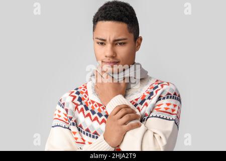 Kranker afroamerikanischer Typ mit Halsschmerzen auf grauem Hintergrund Stockfoto