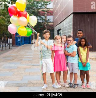 Porträt von glücklichen Tweens mit Ballons auf der Straße der Stadt Stockfoto