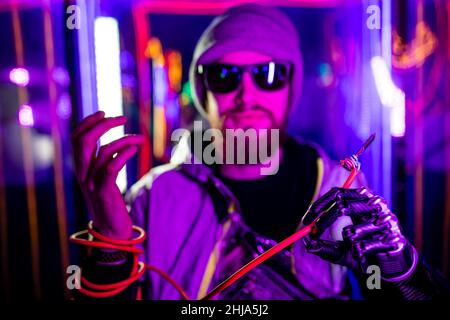 Hübscher junger Mann mit Metallbionik-Prothesenarm, umwickelt auf Draht im Neon-Hintergrund Stockfoto