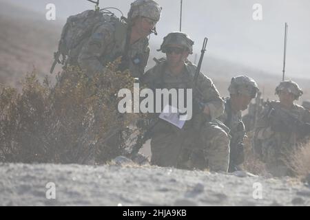 FORT IRWIN, Kalifornien – nach Tagen der Planung, der Proben, Und während der Durchführung von Missionen im sandigen Hintergrund der Mojave-Wüste hielten maskierte Anführer des Stryker Brigade Combat Teams der 7th Infantry Division 1-2 am 17. Januar 2022 das Training für eine Nachbesprechung an, um im National Training Center, Fort Irwin, Kalifornien, die während der entscheidenden Aktionsrotation 22-03 erlernten operativen Lektionen zu besprechen. Stockfoto