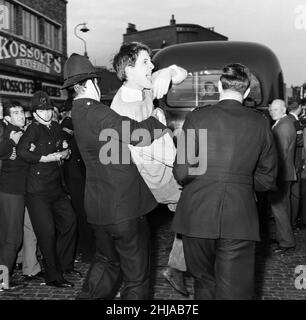 Eine große Menge versammelte sich in der Ridley Road, E8, um gegen den ehemaligen faschistischen Führer Sir Oswald Mosley und Mitglieder seiner antisemitischen Blackshirt-Gruppe zu demonstrieren, die eine Kundgebung im Londoner East End geplant hatten. Mosley und seine Gruppe wurden angegriffen und zu Boden geschlagen, sobald sein Treffen in der Ridley Road, Dalston, eröffnet wurde. Die Polizei schloss das Treffen innerhalb der ersten drei Minuten ab und verhaftete 54 Personen, darunter Sir Oswalds Sohn Max. Die Polizei hält einen der wütenden Demonstranten zurück. 31st. Juli 1962. Stockfoto