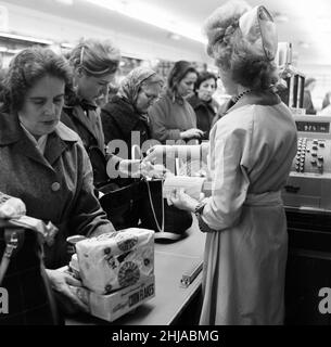 Shopper, Fine Fare Supermarket, Wilton, London, 29th. Oktober 1963. Sammeln Sie Green Shield Briefmarken an der Kasse, nachdem Sie für Waren bezahlt haben. Green Shield Stamps ist ein britisches Verkaufsförderungsprogramm, das Käufer mit Briefmarken belohnt, die eingelöst werden können und zum Kauf von Geschenken aus einem Katalog oder einem angeschlossenen Einzelhändler verwendet werden. Stockfoto