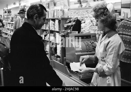 Shopper, Fine Fare Supermarket, Wilton, London, 29th. Oktober 1963. Sammeln Sie Green Shield Briefmarken an der Kasse, nachdem Sie für Waren bezahlt haben. Green Shield Stamps ist ein britisches Verkaufsförderungsprogramm, das Käufer mit Briefmarken belohnt, die eingelöst werden können und zum Kauf von Geschenken aus einem Katalog oder einem angeschlossenen Einzelhändler verwendet werden. Stockfoto