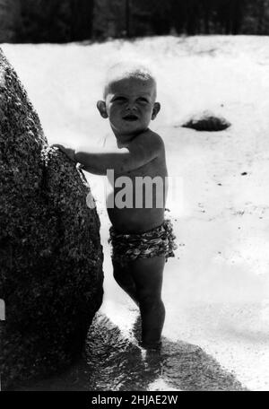 Prinz Edward von Kent - der Herzog von Kent Eine besondere Bildergruppe, die der Herzog von Kent von seinem Sohn, dem Earl of St Andrews, aufgenommen hat, der am 26. Juni 1963 seinen ersten Geburtstag feiert - der Earl knöcheltief im Wasser klammert sich zur Beruhigung an einen Felsen Stockfoto