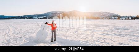 Winterspaß. Banner von Mädchen machen Schneemann im Winter See Schnee Natur Landschaft. Panoramablick Stockfoto