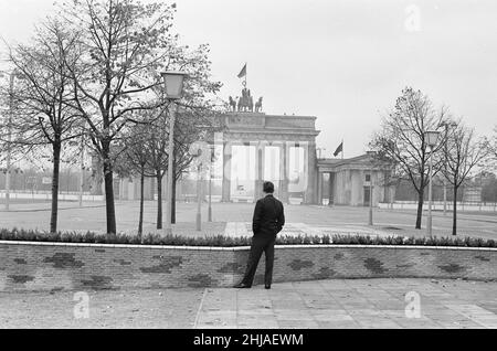 Szenen in Berlin, drei Jahre nach Beginn der Arbeiten am Bau der Berliner Mauer, die Ost und West trennt. Ein Bürger mit Blick auf das Brandenburger Tor am Pariser Platz. 25th. Oktober 1964. Stockfoto