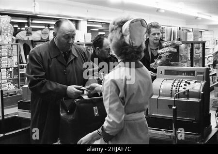 Shopper, Fine Fare Supermarket, Wilton, London, 29th. Oktober 1963. Sammeln Sie Green Shield Briefmarken an der Kasse, nachdem Sie für Waren bezahlt haben. Green Shield Stamps ist ein britisches Verkaufsförderungsprogramm, das Käufer mit Briefmarken belohnt, die eingelöst werden können und zum Kauf von Geschenken aus einem Katalog oder einem angeschlossenen Einzelhändler verwendet werden. Stockfoto