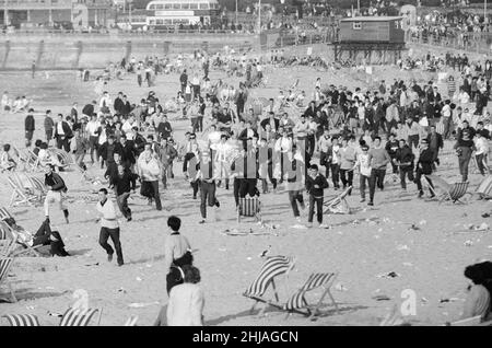 Mods gegen Rockers. Bild zeigt die Szene in Margate, North East Kent im Mai 1964. Mods laufen über den Strand und stören die Urlauber, während sie gehen. Bild aufgenommen am 17th. Mai 1964 Stockfoto