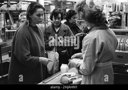 Shopper, Fine Fare Supermarket, Wilton, London, 29th. Oktober 1963. Sammeln Sie Green Shield Briefmarken an der Kasse, nachdem Sie für Waren bezahlt haben. Green Shield Stamps ist ein britisches Verkaufsförderungsprogramm, das Käufer mit Briefmarken belohnt, die eingelöst werden können und zum Kauf von Geschenken aus einem Katalog oder einem angeschlossenen Einzelhändler verwendet werden. Stockfoto