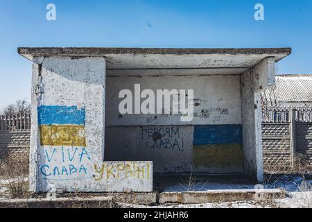 Eine Bushaltestelle mit Schüssen und dem Graffiti "Glory to Ukraine" in einem Dorf in der Nähe der Front, im Donbass-Krieg. Seit 2014 findet in der Ostukraine in den Oblast Donezk und Lugansk ein Krieg statt. Dieses Gebiet steht im Streit zwischen ukrainischen Truppen und prorussischen Rebellen. Stockfoto