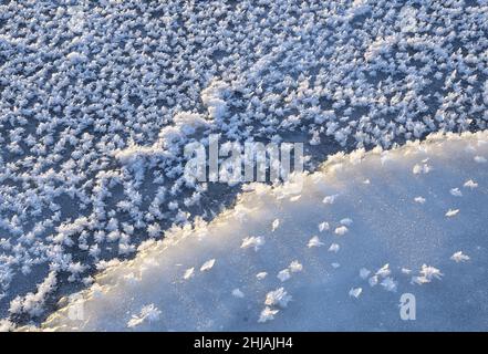 Große Schneeflocken aus nächster Nähe auf dem ersten blauen Eis des Flusses. Reine Schneekristalle. Abstrakter blau-blauer Hintergrund. Die Natur Sibiriens, 2018 Stockfoto