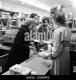 Shopper, Fine Fare Supermarket, Wilton, London, 29th. Oktober 1963. Sammeln Sie Green Shield Briefmarken an der Kasse, nachdem Sie für Waren bezahlt haben. Green Shield Stamps ist ein britisches Verkaufsförderungsprogramm, das Käufer mit Briefmarken belohnt, die eingelöst werden können und zum Kauf von Geschenken aus einem Katalog oder einem angeschlossenen Einzelhändler verwendet werden. Stockfoto