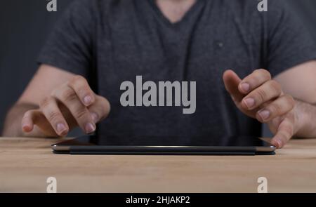 Nahaufnahme eines Mannes, der auf einer Tablette tippt Stockfoto
