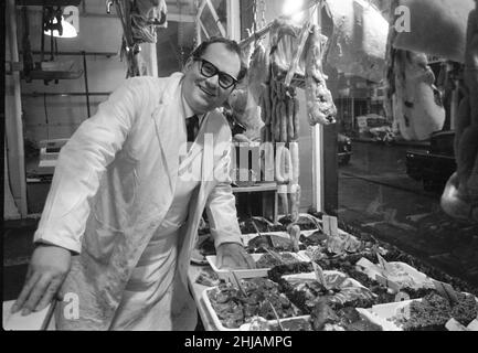Metzger steht stolz in seinem Laden, als seine verschiedenen Fleischprodukte im Fenster Februar 1963 angezeigt werden. Stockfoto