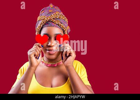 Attraktive schöne Frau aus dem Süden mit Turban hält in den Händen Herz isoliert über rotem Hintergrund valentinstag 14. februar Stockfoto