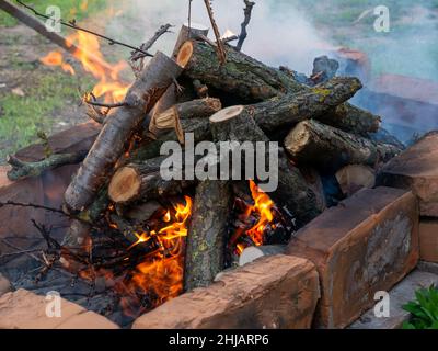 Brüllendes Feuer mit verschwommenen Flammen aus Holzstämmen in einer Steinfeuerstelle Stockfoto