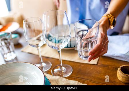 Porträt einer jungen, schönen kaukasischen Frau, die ein Geschirr wascht und den Tisch bei Tageslicht einlegt Stockfoto