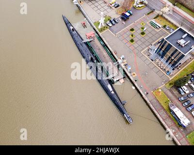 Ein schwarzes U-Boot tauchte im Stadthafen auf dem Wasser auf. Stockfoto