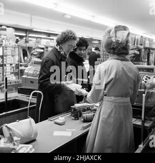 Shopper, Fine Fare Supermarket, Wilton, London, 29th. Oktober 1963. Sammeln Sie Green Shield Briefmarken an der Kasse, nachdem Sie für Waren bezahlt haben. Green Shield Stamps ist ein britisches Verkaufsförderungsprogramm, das Käufer mit Briefmarken belohnt, die eingelöst werden können und zum Kauf von Geschenken aus einem Katalog oder einem angeschlossenen Einzelhändler verwendet werden. Stockfoto