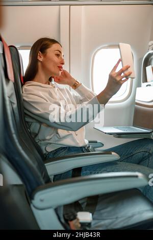 Junge Frau macht Selfie im Passagierflugzeug Stockfoto
