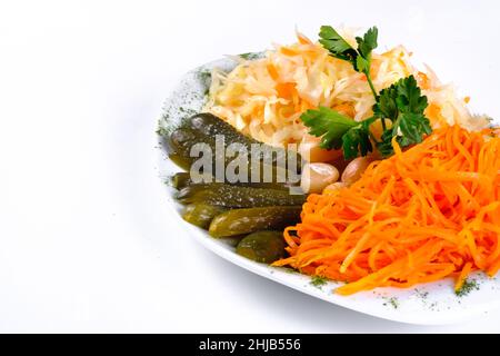 Eingelegtes Gemüse, Gurke, Karotte, Knoblauch, Kohl auf einem Teller auf einem weißen isolierten Hintergrund. Stockfoto