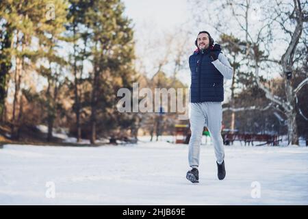 Der Erwachsene Mann trainiert im Winter im Park. Er joggt. Stockfoto