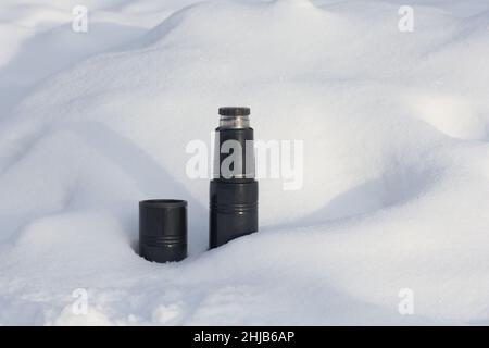 Thermoskanne und Tasse auf Schnee Drift im Winter Park Stockfoto