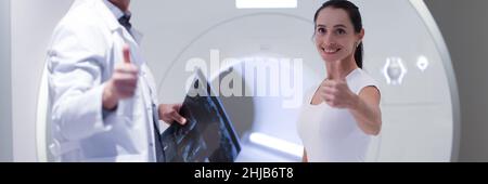 Lächelnder Arzt und Patientin halten die Daumen im Büro für die MRT-Untersuchung hoch Stockfoto