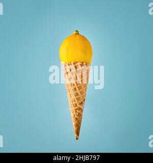 Eiskegel mit frischer Zitrone auf blauem Hintergrund. Minimales Lebensmittelkonzept. Stockfoto