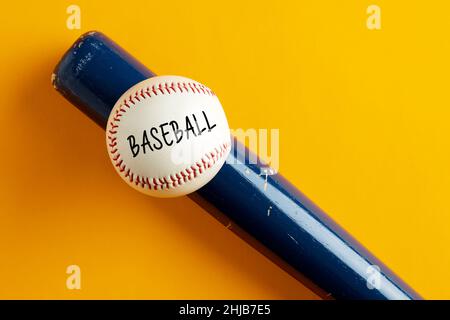 Baseballball auf einem Holzschläger mit dem Wort Baseballspiel auf gelbem Hintergrund. Baseballspiel. Stockfoto