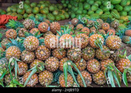 Viele Ananas und Wassermelonen am Boden auf dem Lebensmittelmarkt in Sansibar, Tansania Stockfoto