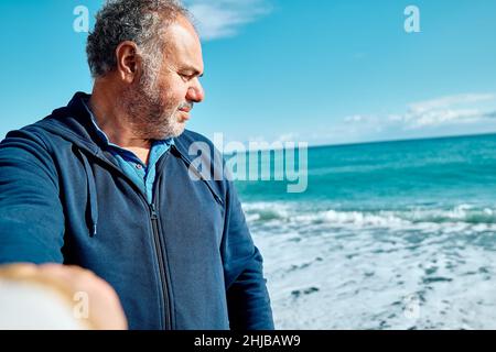 Folge mir. Der Mann hält und zieht die Hand des Fotografen, während er am Strand läuft und führt sie zum Meer. Konzept der Vereinigung und sorglos modern Stockfoto