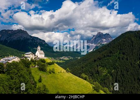 Die Kirche Chiesa Santa Lucia in Colle Santa Lucia am Fuße des Giau-Passes, Passo di Giau, der Gipfel des Monte Pelmo in der Ferne. Stockfoto