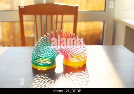 Anti-Stress-Zauberring Frühling Regenbogen Sprungspielzeug auf Tisch in sonnigen Raum zu Hause, selektive Fokus. Stressabbau und Anti-Angst-Spielzeug Konzept Stockfoto