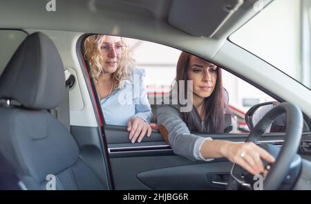 Die Verkäuferin zeigt den Innenraum des Kundenwagens im Händlershop. Stockfoto