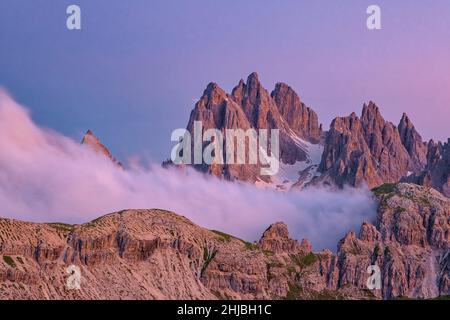 Der Berg Cadini di Misurina, von der Hütte Rifugio Auronzo aus gesehen, bei Sonnenuntergang. Wolken steigen aus dem Tal. Stockfoto