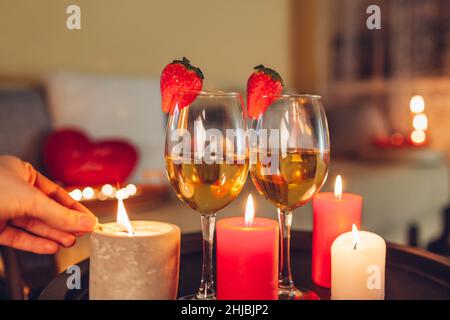 Frau schmückt Tischgestaltung für Valentinstag Feier zu Hause Beleuchtung Kerzen auf dem Tisch von Weingläsern Stockfoto