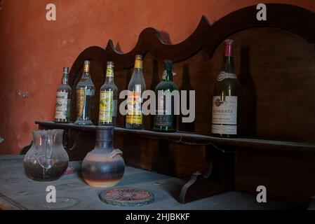 September 2021, Italien. Alte Flaschen Wein und Spirituosen, die in einem verlassenen Haus auf einem Möbelstück abgelegt wurden. Urbex Stockfoto