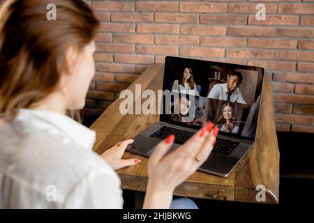 Rückansicht einer weiblichen Mitarbeiterin, die eine Online-Konferenz mit Kollegen mit einem Laptop führt. Junge Geschäftsfrau diskutiert mit Unternehmensprojekt Stockfoto