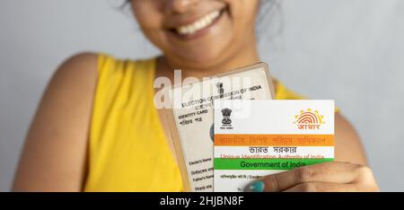 Birbhum, Westbengalen / Indien - 21st. Dezember 2021: Selektiver Fokus auf Aadhaar und Wählerkarte Indiens in der Hand einer jungen Inderin mit Smili Stockfoto