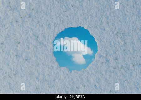 3D Darstellung eines kreisförmigen Spiegels, der eine einzelne weiße Wolke reflektiert und von Schnee umgeben ist. Flaches Lay-Design im Winterstil Stockfoto