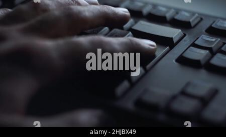 Nahaufnahme Mann drückt Tastatur-Taste. Mann drückt Taste geben Computertastatur. Die Hand des Mannes drückt die Tastatur im Licht des Computerbildschirms. Stockfoto