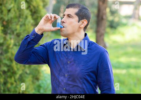 Der Mensch verwendet einen Asthmainhalator in einem Park Stockfoto