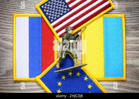 Soldatenfigur auf Fahnen von Russland, der Ukraine, den Vereinigten Staaten und der EU, Ukraine-Krise Stockfoto
