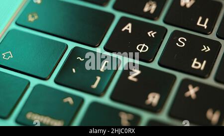 Nahaufnahme eines Laptops oder einer Computertastatur. Konzept der modernen Geräte und Technologien, Tasten einer schwarzen Tastatur unter dem grünen Licht. Stockfoto