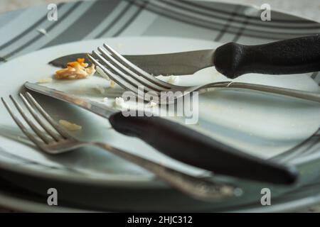 Essensreste auf leerem Teller mit Gabel und Messer Stockfoto