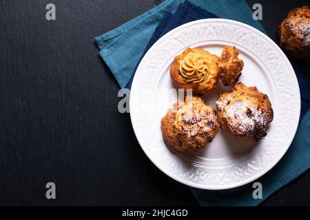 Lebensmittelkonzept hausgemachte Caramel Choux a la Cream oder Choux Cream Puffs auf dunklem Hintergrund mit Kopierfläche Stockfoto