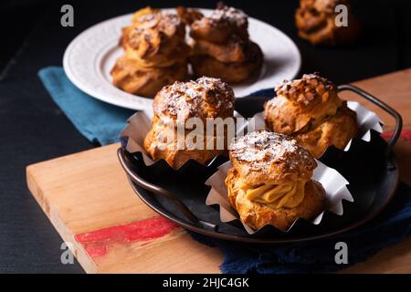 Lebensmittelkonzept hausgemachte Caramel Choux a la Cream oder Choux Cream Puffs auf dunklem Hintergrund mit Kopierfläche Stockfoto